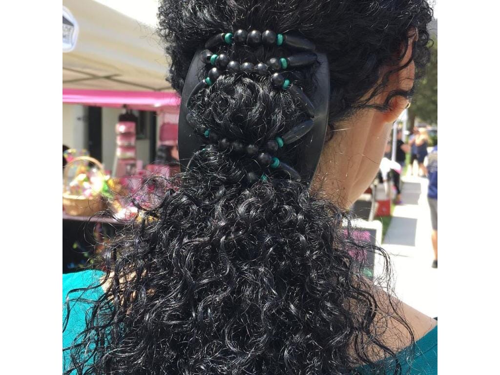Woman at a craft fair wearing an African Butterfly Beada Thick Hair Comb with teal and black wood beads, in a low ponytail hairstyle