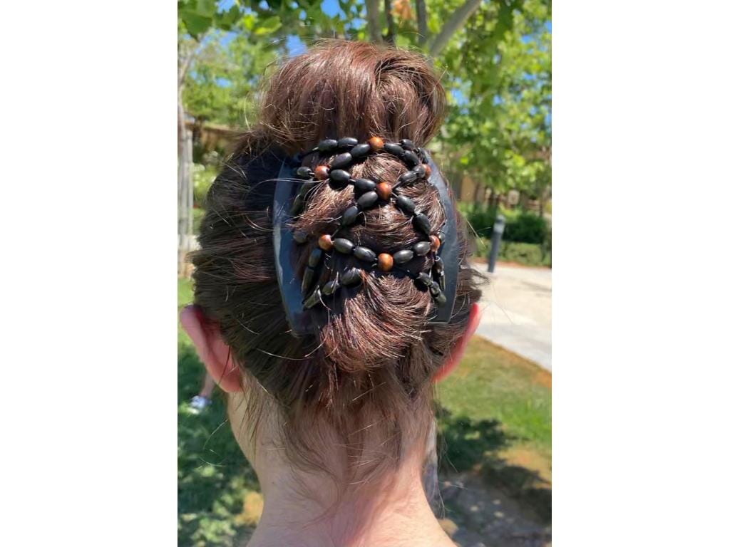 Woman outdoors wearing a black African Butterfly Ndebele Thick Hair Comb in a bun hairstyle adorned with black and brown beads