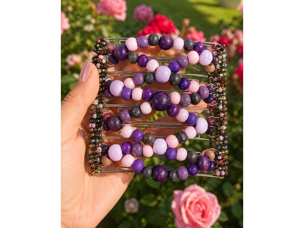 Woman holding an African Butterfly Wire Hair Clip 11 Tong in a rose garden, purple and pink wood beads, warm sunlight