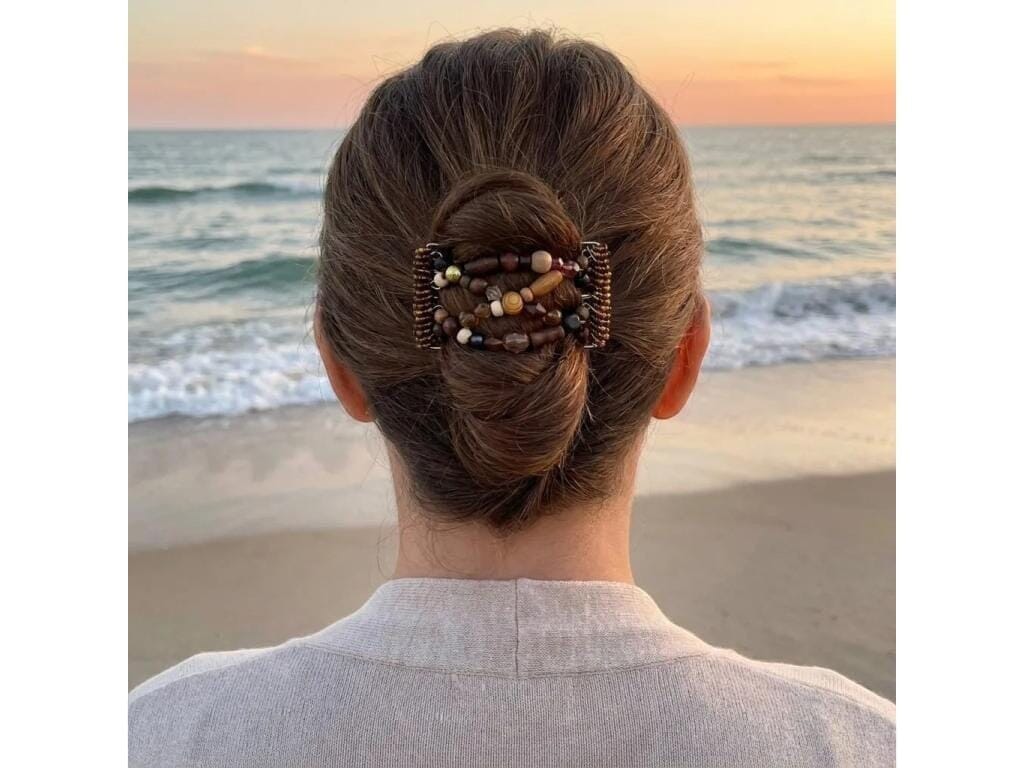 Woman wearing an African Butterfly 5 Tong Wire Hair Clip in a bun hairstyle at sunset on the beach
