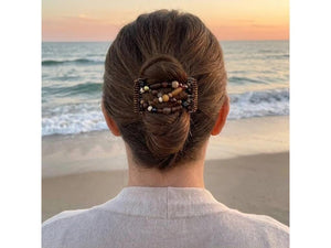 Woman wearing an African Butterfly 5 Tong Wire Hair Clip in a bun hairstyle at sunset on the beach