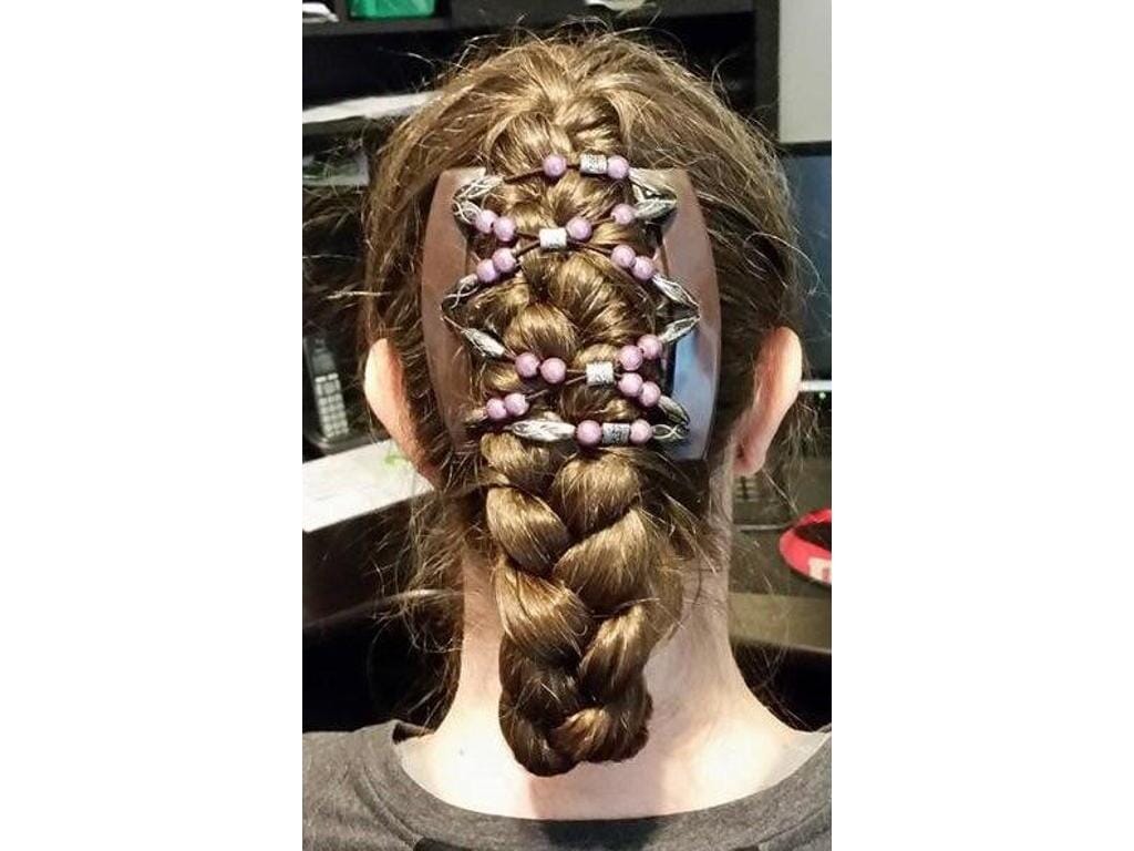 Woman sitting at a desk wearing an African Butterfly Dalena Brown Thick Hair Comb, silver shimmer, mauve, and black with silver beads, in a braided updo