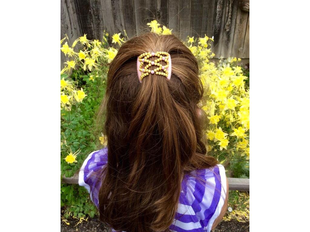 Young girl wearing an African Butterfly Pink Pearl LadyBug Hair Comb with pink and yellow beads in a sides up hairstyle in a yellow flower garden