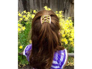 Young girl wearing an African Butterfly Pink Pearl LadyBug Hair Comb with pink and yellow beads in a sides up hairstyle in a yellow flower garden