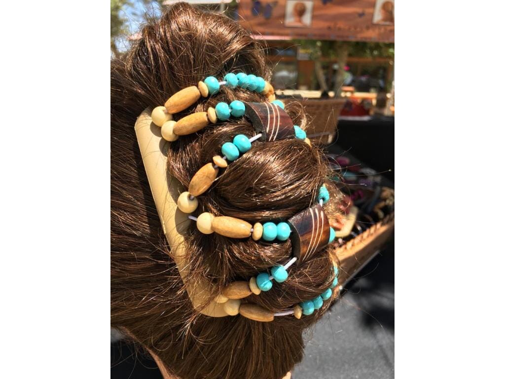 African Butterfly Hair Comb - woman with dark brown hair wearing Stones & Bones Blonde Hair Comb with turquoise and natural wood beads, outdoor artisan market setting, back view, in a french twist hairstyle