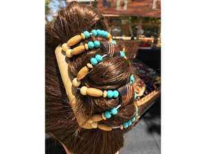 African Butterfly Hair Comb - woman with dark brown hair wearing Stones & Bones Blonde Hair Comb with turquoise and natural wood beads, outdoor artisan market setting, back view, in a french twist hairstyle